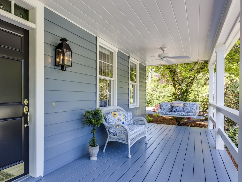 Clean front porch with painted boards, a wicker chair and a swing