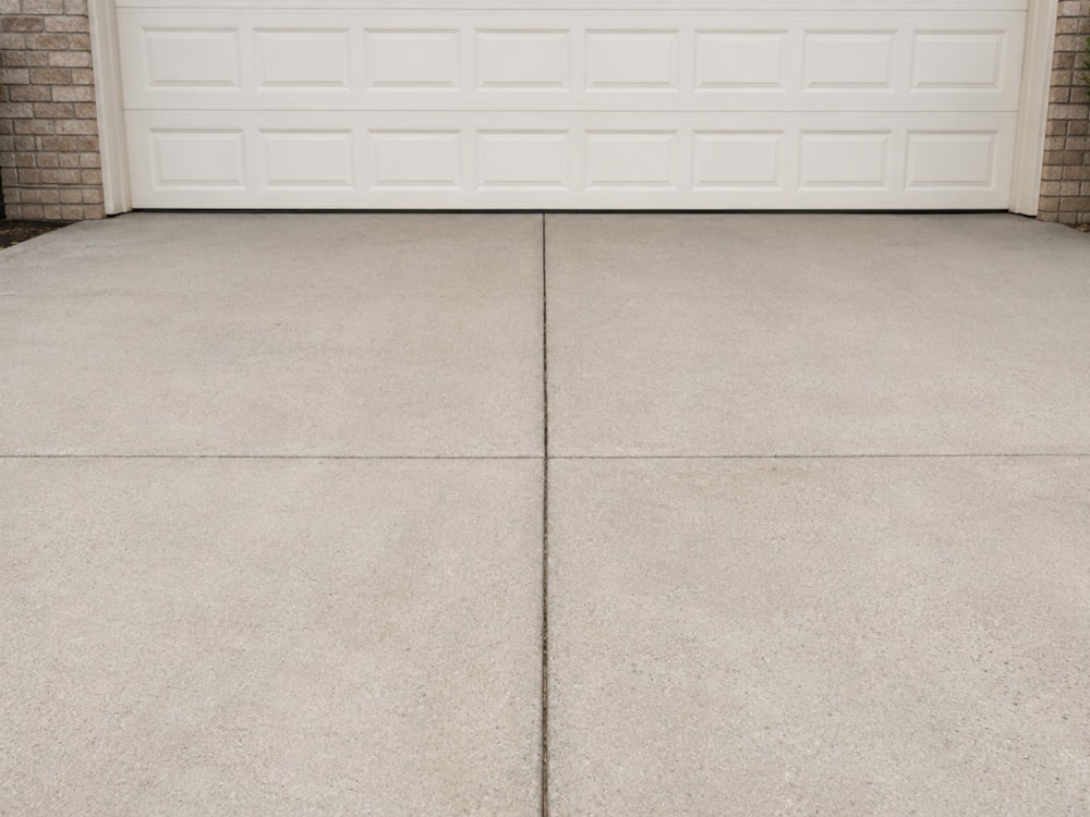 Spotless concrete driveway in front of a white garage door